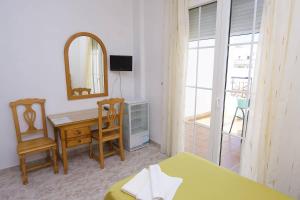 Cette chambre comprend un bureau, une table et un miroir. dans l'établissement HOTEL DON FELIPE, à Carboneras