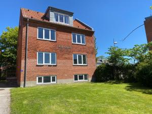 a red brick building with white windows on a yard at Malthe Bruuns Vej 17, 1. sal in Thisted