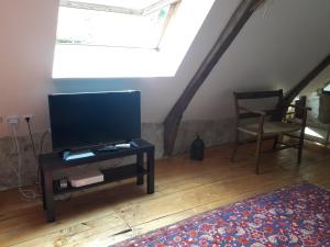 a living room with a flat screen tv and a chair at Charme, jardin et vue panoramique en plein coeur de St-Cirq in Saint-Cirq-Lapopie