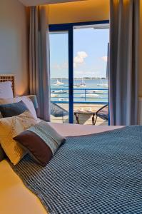 een slaapkamer met een bed en uitzicht op de oceaan bij Hotel Restaurant Les Venetes in Arradon