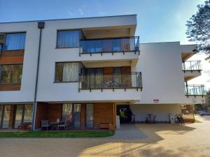 un edificio blanco con balcones y mesas. en Enklawa Mielno-Unieście przy plaży en Unieście