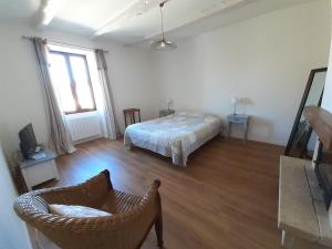 ein Schlafzimmer mit einem Bett und einem Stuhl in einem Zimmer in der Unterkunft Charme, jardin et vue panoramique en plein coeur de St-Cirq in Saint-Cirq-Lapopie