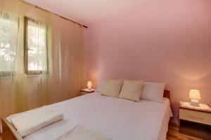a bedroom with a white bed and a window at Biserka apartments near the beach and center in Mali Lošinj