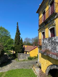 a yellow building with red windows and a tree at Quinta da Boa Viagem in Viana do Castelo