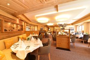 a restaurant with white tables and chairs and wooden ceilings at Hotel Jagdhof in Riezlern