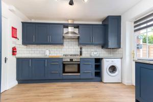 cocina con armarios azules, lavadora y secadora en Avella by the Park en Lytham St Annes