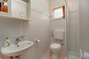 a white bathroom with a toilet and a sink at Biserka apartments near the beach and center in Mali Lošinj +17 photos