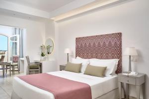 a bedroom with a large white bed with a pink blanket at Stelia Mare Boutique Hotel in Naousa