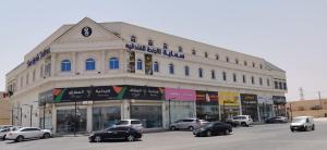un gran edificio con coches estacionados frente a él en سماية للأجنحة الفندقية, en Riad