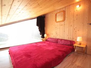 a red bed in a room with a large window at Appartement Les Saisies, 2 pièces, 5 personnes - FR-1-293-205 in Les Saisies