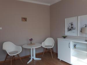 una cocina con 2 sillas blancas y una mesa en KWATERA en Gdansk