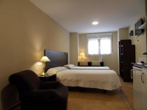 a hotel room with two beds and a chair at Hostal El Estudio in Almansa
