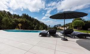 a patio with an umbrella and chairs and a pool at Villa Bella in Benissa