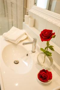 un lavabo con 2 rosas rojas en un jarrón en Villa Rachel Trilo, en Intra 20 fotos más