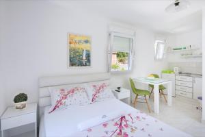 a white bedroom with a bed and a desk at Studios Merdović in Budva