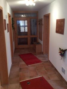 einen Flur mit Tür und roten Teppichen auf dem Boden in der Unterkunft Ferienwohnung Hörmann in Langdorf