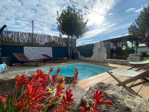 a swimming pool in a yard with a bench and flowers at Ô Chambres d'Hôtes in Le Gua