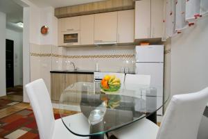 una cucina con tavolo in vetro ed elettrodomestici bianchi di Apartman Oaza mira a Zlatibor