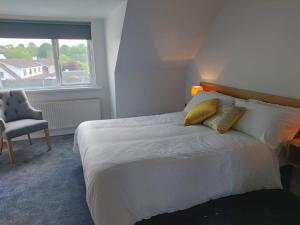 a bedroom with a bed and a chair and a window at Castle Lodge Kilkenny in Kilkenny