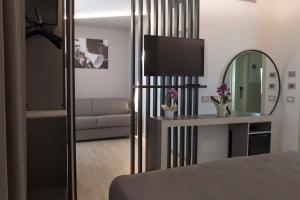 リミニにあるホテル ラ グラディスカのベッドルーム1室(ベッド1台、鏡、ソファ付)