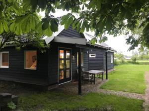 a black house with a picnic table in the yard at IJSSELMEER Lake houses in Andijk