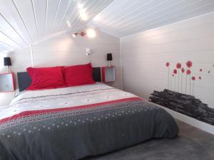 a bedroom with a large bed with red pillows at Un Petit Coin de Vendé in La Flocellière