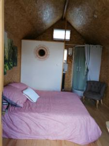 ein Schlafzimmer mit einem rosa Bett und einem Stuhl in der Unterkunft Le petit Radieux in Gémozac