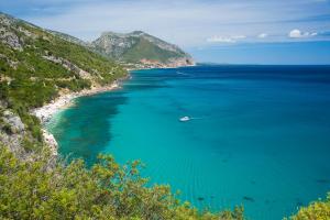 a boat in the water next to a beach at Costa Dorada in Cala Gonone