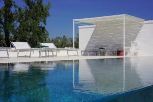 a swimming pool with chairs and a pavilion at Masseria Pezze Galere Piscina privata in Fasano