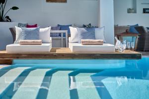 two white couches sitting next to a swimming pool at Stelia Mare Boutique Hotel in Naousa