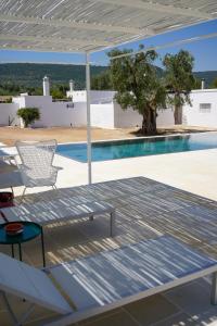 een patio met een tafel en stoelen en een zwembad bij Masseria Pezze Galere Piscina privata in Montalbano
