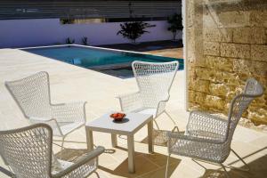 a group of chairs and a table next to a pool at Masseria Pezze Galere Piscina privata in Fasano