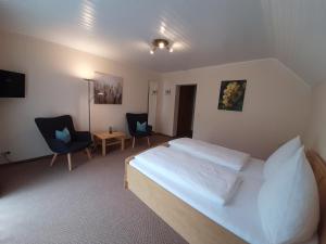 a bedroom with a white bed and two chairs at Haus Weingarten APPARTEMENTS-ZIMMER in Ernst