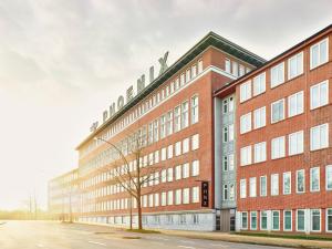 un gran edificio de ladrillo con un árbol delante de él en PHNX Aparthotel Hamburg en Hamburgo