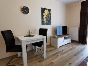 um quarto com uma mesa e cadeiras brancas e uma televisão em Haus Weingarten APPARTEMENTS-ZIMMER em Ernst
