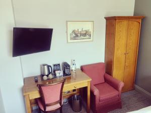 um quarto com uma secretária com 2 cadeiras e uma televisão em The Greyhound Inn em Gerrards Cross