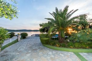 a walkway with two palm trees and a body of water at Apartments Villa Punta Royal in Pirovac
