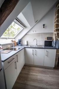 cocina con armarios blancos, fregadero y ventana en OHARA en Dinan