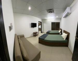 Habitación con 2 camas y sofá. en • Faizi Furnished Apartments, en Faisalabad