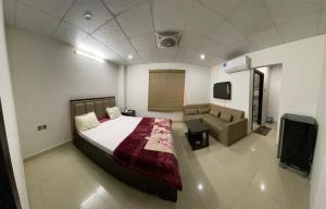 1 dormitorio con cama, sofá y TV en • Faizi Furnished Apartments, en Faisalabad