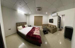a bedroom with a bed and a couch and a tv at • Faizi Furnished Apartments in Faisalabad