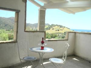 una mesa con una botella de vino y 2 sillas en el balcón en Sardinia Yellow House, en Solanas