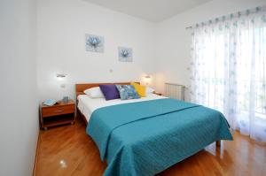 a bedroom with a large bed with a blue blanket at Apartments Roza in Trogir