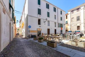 un callejón con mesas y sillas en un edificio en La finestra sul teatro, en Alghero