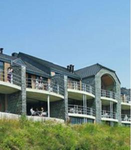 a building with people sitting on the balconies of it at Zonnig Appartement Golf van Durbuy in Durbuy