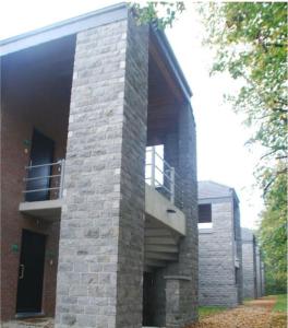 a brick building with a balcony on the side of it at Zonnig Appartement Golf van Durbuy in Durbuy