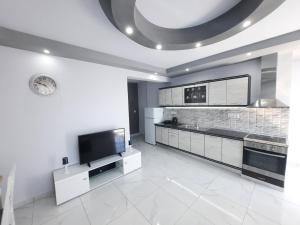a kitchen with white cabinets and a flat screen tv at Panorama Apartments in Prinos +17 photos