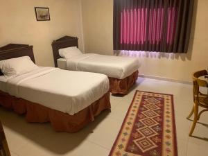 - 2 lits dans une chambre avec un tapis et une fenêtre dans l'établissement Nonna Aisha B&B, à Wadi Musa