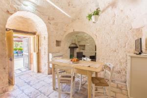 a kitchen with a table and chairs in a stone wall at Trullo Pioppo gigante - jacuzzi in San Michele Salentino