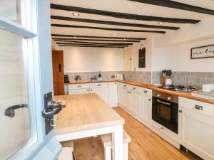 a kitchen with white cabinets and a wooden counter top at Ivy Cottage in Matlock